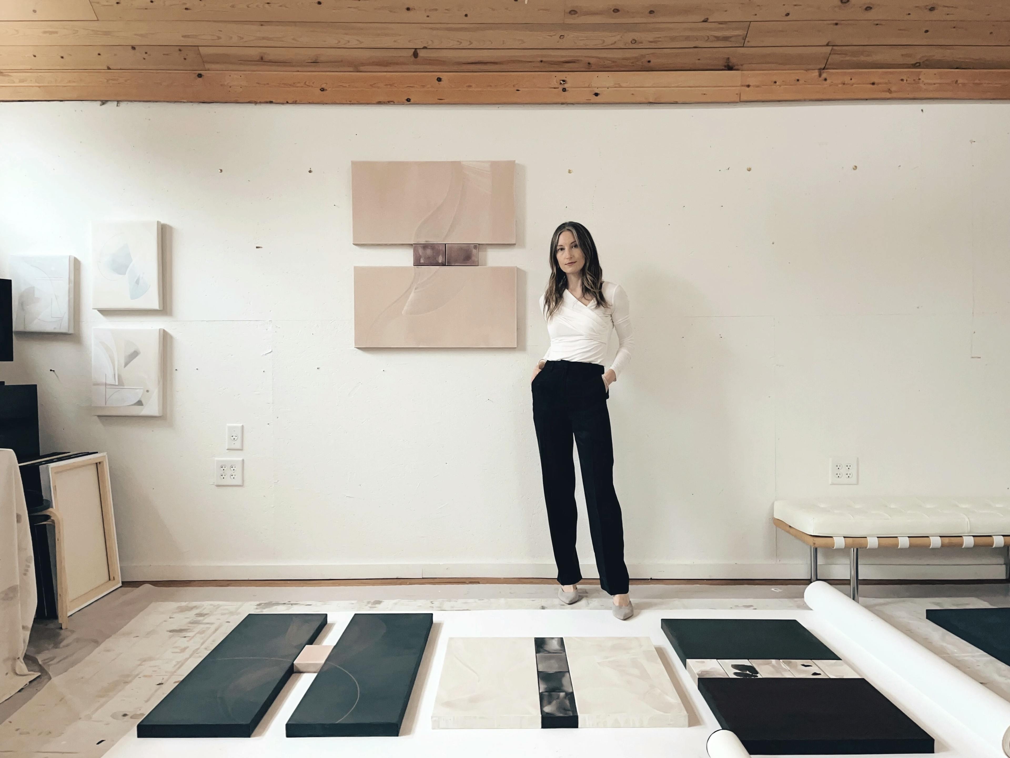 Artist Laura Naples standing in her studio surrounded by her diptych paintings.